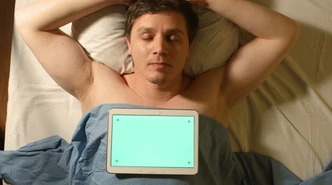 A young man speeps. A tablet PC lays on him (green screen) Stock Footage 60642256