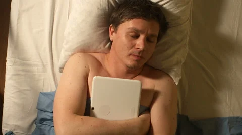 A young man speeps with a tablet PC at his hands Видео 60642370