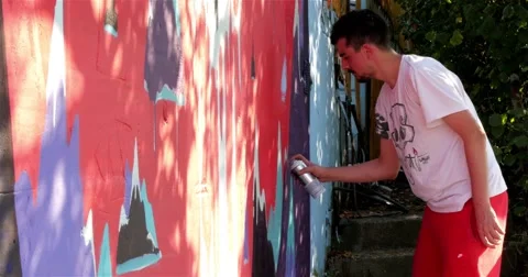 Young man spraying graffiti on the wall, street performance, artwork, mural, 4k 스톡 동영상 54867092