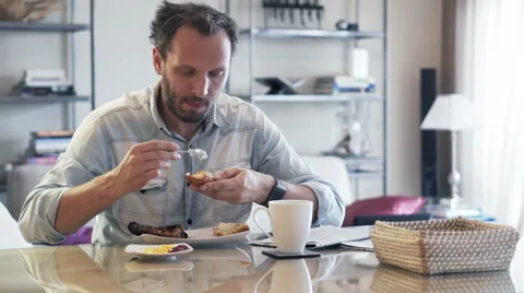 Young man spreading jam during breakfast by dinning table at home HD Stock Footage 57540230