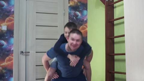 A young man squats with his son on his back. fitness classes. exercises at home Stock Footage 171012797