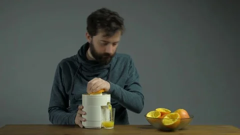 Young Man with Squeezer Squeezing Orange Juice Isolated Grey Background Stock Footage 76521786