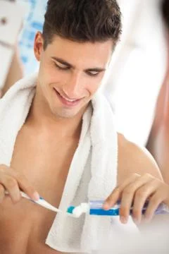 Young man squeezes toothpaste on the brush 스톡 사진