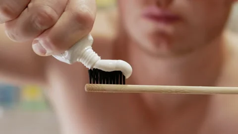A young man squeezes toothpaste onto a toothbrush Stock Footage 212049058
