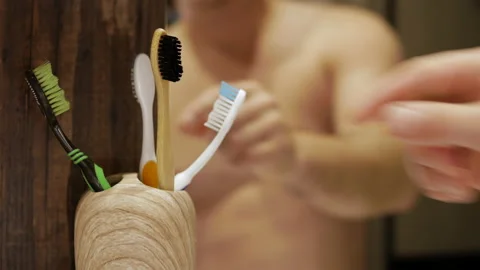 A young man squeezes toothpaste onto a toothbrush in the bathroom. Stock Footage 212052741