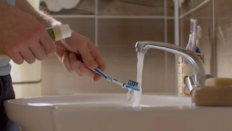Young man squeezing toothpaste onto a brush Stock Footage 128696109
