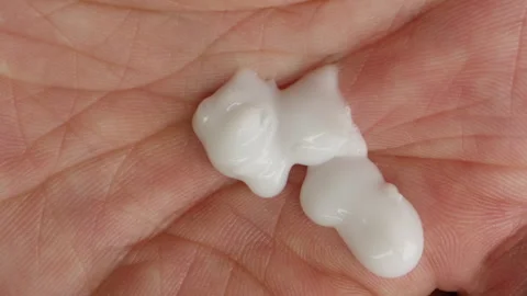 Young man squeezing a white moisturizer from a tube on his hand close-up Stock Footage 257089371
