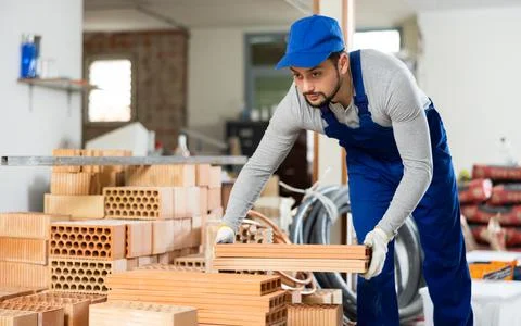 Young man stacking bricks at construction site Stockfoto's