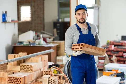 Young man stacking bricks at construction site 写真素材