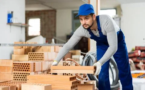 Young man stacking bricks at construction site 写真素材