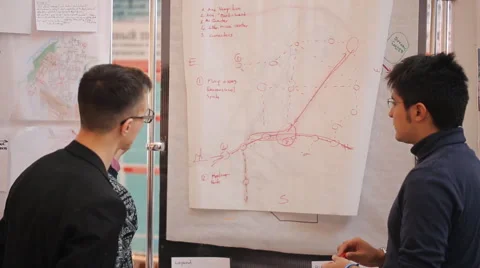 The young man by the stand explains and shows something to the other two Stock Footage 64296445