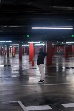 Young man standing alone in an empty parking garage Stock Photos