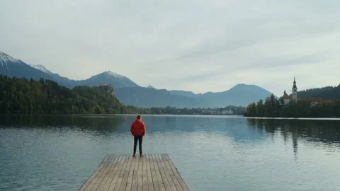 Young man standing alone on lake footbridge and admires sunrise on a lake. Video stock 201164922
