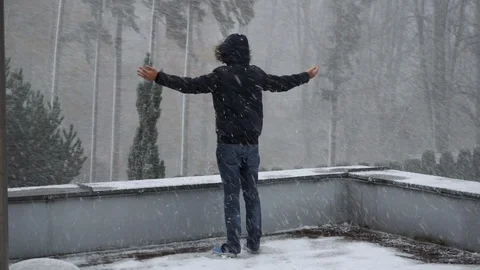 Young man standing and shouting in Snowstorm with his arms raised up. Winter. Stockbeeldmateriaal 128986690