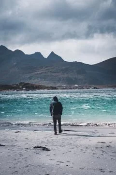 Young man standing at the beach with clouds and blue sky the sea at Ramberg Stock Photos