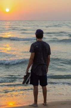 The young man is standing on the beach. Stock Photos