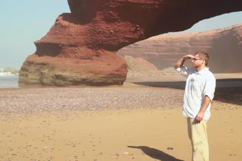 Young man standing on the beach, steadicam shot Stockbeeldmateriaal 10892387