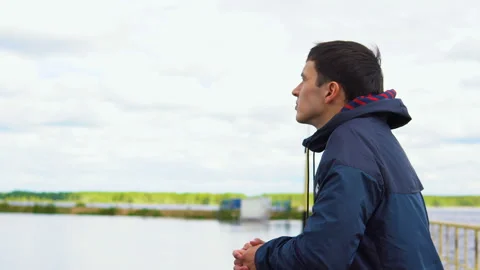 A young man is standing on a bridge and looking into the distance. Video stock 90894087