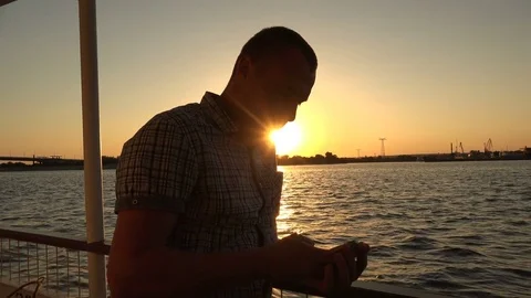 A young man is standing on the deck of a motor ship and looking into the phone Stock Footage 85365359