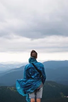 Young man standing on the edge of the mountain and looking forward Stock Photos