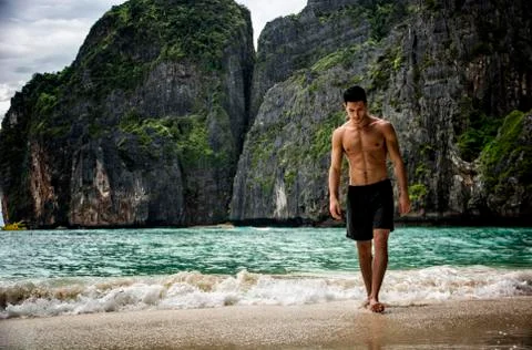 Young man standing on edge of the ocean Stock Photos