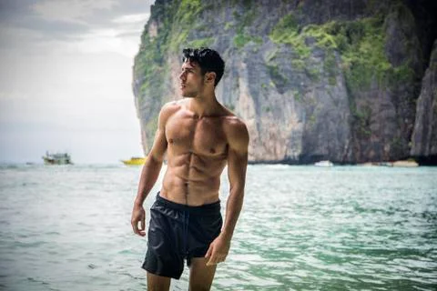 Young man standing on edge of the ocean Stock Photos