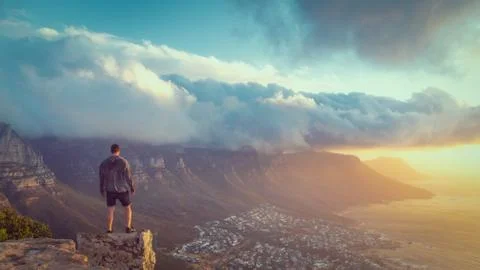 Young man standing on the edge at the top of Lion's head mountain in Cape Tow Stock Photos
