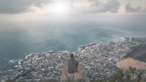 Young man standing on the edge at the top of Lion's head mountain in Cape Tow Stock Photos