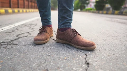 Young man standing on empty road with brown casual shoes on Stock Footage