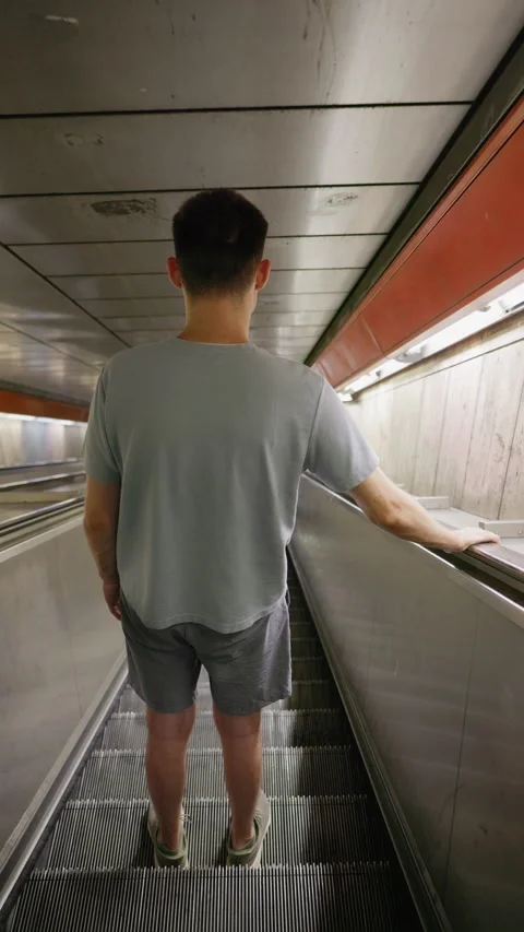 Young man standing on escalator descending underground Stock Footage 332781847