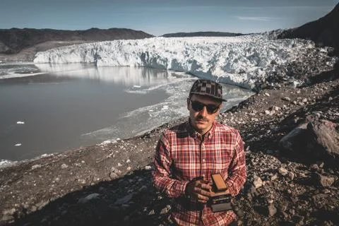 A young man standing in front of Eqip Sermia glacier called Eqi Glacier. Tourist Stock Photos