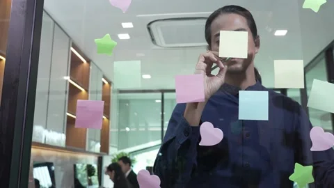 Young man standing in front of many post-it notes on the glass wall Stock Footage 171967037