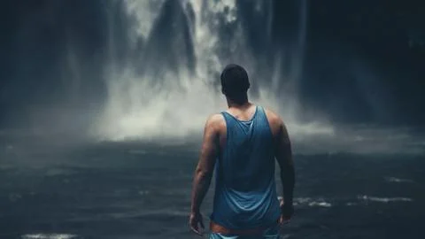 Young man standing in front of powerful Nungnung waterfall on Bali Stock Photos