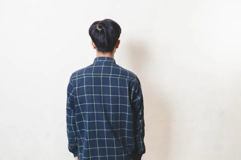 Young man standing with his back facing the camera, showing a rear view aga.. Stock Photos
