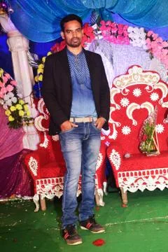 Young man standing in a marriage function wearing black jacket and jeans Stock Photos