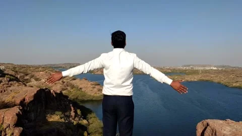 A young man standing on the mountain, hands up and enjoy scenery view of the la Stock Footage 234796368