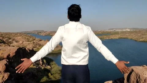  A young man standing on the mountain, hands up and enjoy scenery view of the la Stock Footage 234799356