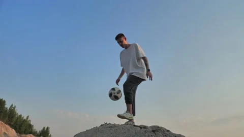 Young man standing on a mountain plays with a ball Stock Footage 133522556