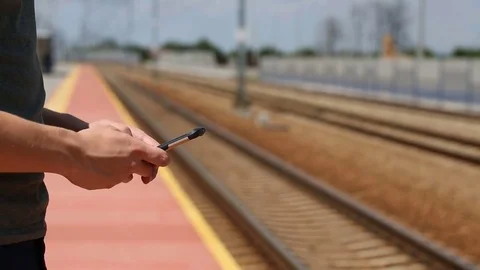 Young man standing next to the rails and texting on smartphone Stock Footage 78653295