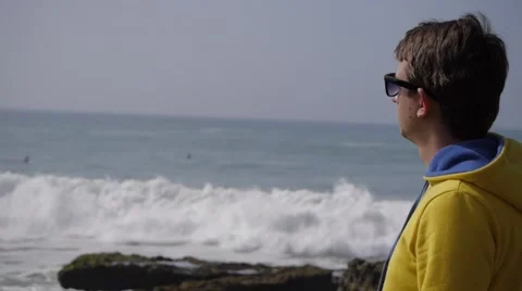 Young man standing on ocean beach looking on waves hd quality 库存影片 58912069