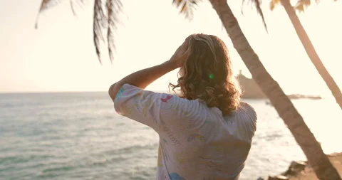 A young man standing by the ocean raises his hands up Stock Footage 105732280