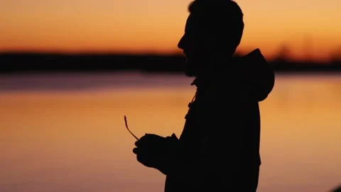 A young man standing by the ocean takes off his glasses from fatigue Stock Footage 172255934