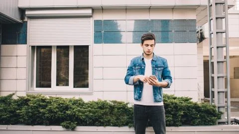 Young man standing outdoors using mobile Foto stock