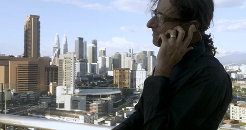 Young man standing outside on a rooftop talking on his mobile phone Stock Footage 86712981