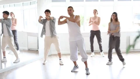 Young man standing performs basic hip hop movements in front of group of Video stock 280952768