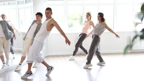 Young man standing performs basic hip hop movements in front of group of Video stock 313458402