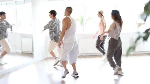 Young man standing performs basic hip hop movements in front of group of Stock Footage 326314272