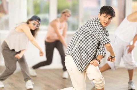 Young man standing performs basic hip hop movements in front of group of Stock Photos