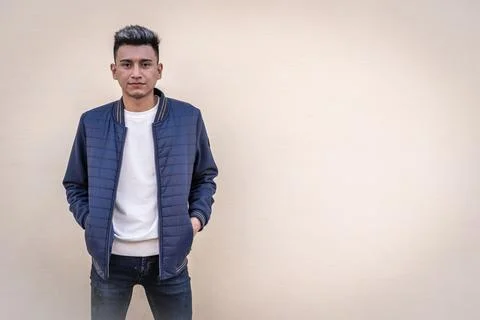Young man standing posing with his hands in pockets of his jacket looking at Stock Photos