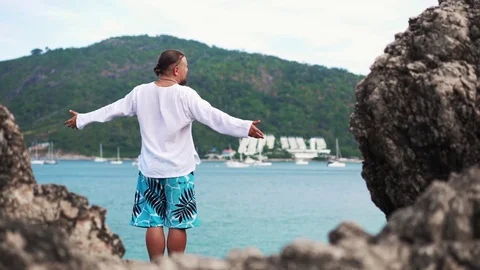 Young man standing on a rock with raised hands Stock Footage 72822306